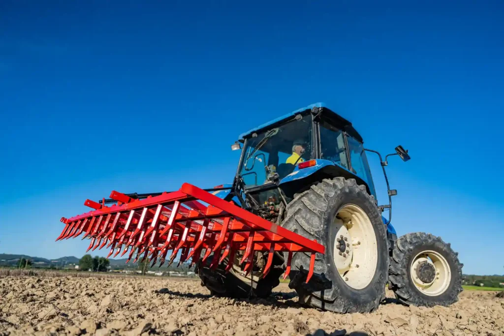 Trattore agricolo durante il lavoro di erpicatura in campo aperto